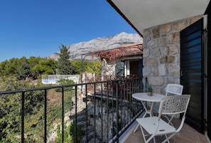 Un balcon avec un mur en pierre, une table blanche et deux chaises blanches.