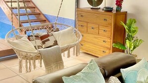 Un salon avec un fauteuil suspendu, un canapé et un meuble en bois.