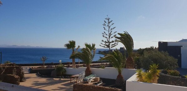 Relax on the rooftop terrace with a serene sea view, surrounded by lush greenery and comfortable lounge seating.