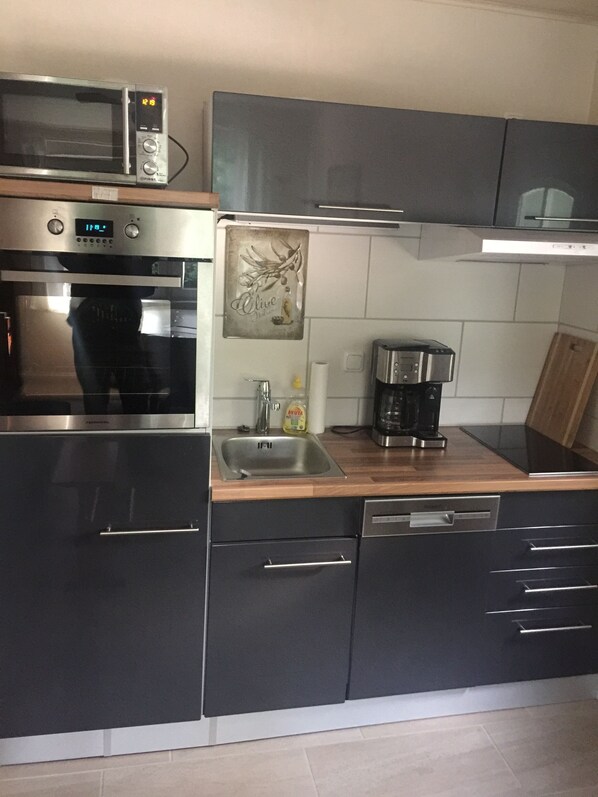 Uma cozinha moderna com eletrodomésticos de aço inoxidável, bancada de madeira e armários escuros.