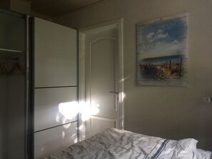 Um quarto com uma cama, um guarda-roupa e uma porta.
