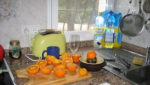 Een keuken met een granieten aanrecht, een broodrooster, een snijplank met sinaasappels, een spoelbak en diverse keukengerei.