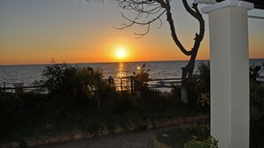 A sunset over the ocean with a view of the sea and a pathway leading to a white structure.
