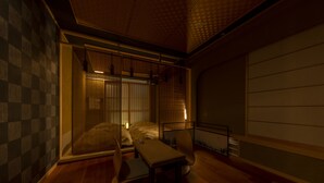 Una habitación tradicional japonesa con suelo de tatami, una mesa baja, una silla y un futón.