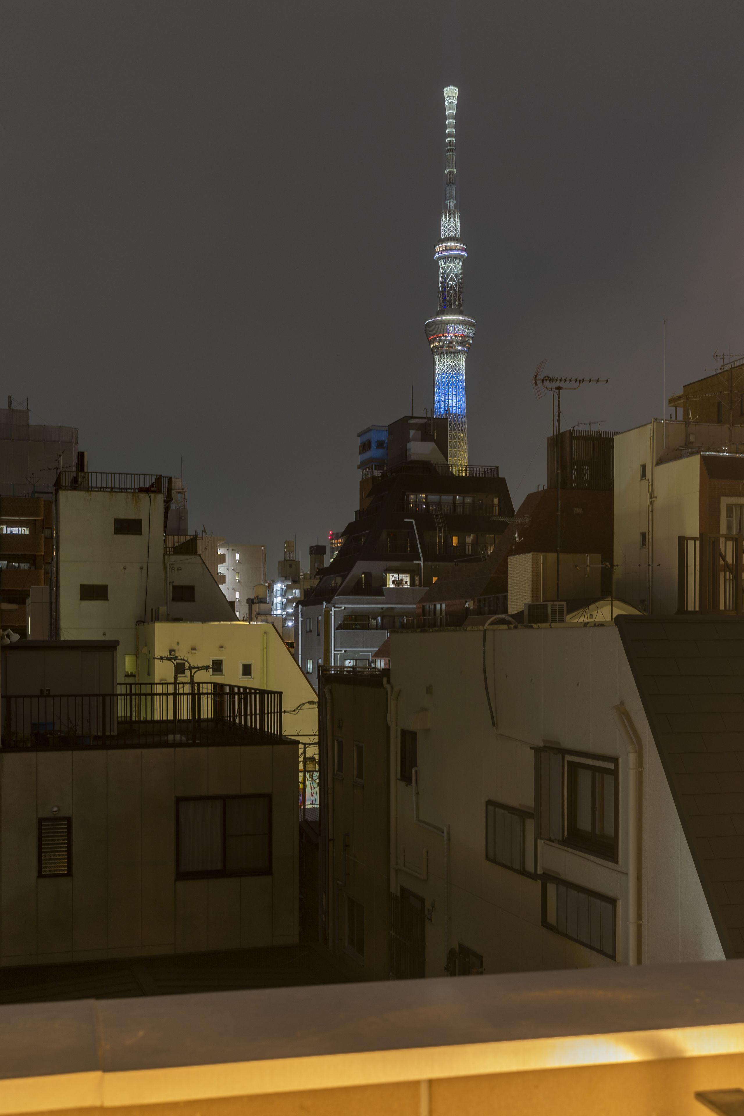 Ein nächtliches Stadtbild, im Hintergrund eine auffällig beleuchtete Turm.