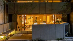 Un edificio moderno de varios pisos con un balcón y un interior luminoso visible a través de las ventanas.