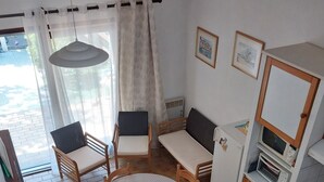 A compact kitchen with a dining table, chairs, a microwave, and a refrigerator.