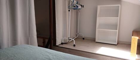 A bedroom with a bed, a wardrobe, a ceiling fan, and a window with curtains.