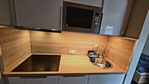 A compact kitchen with a built-in microwave, a sink, and a stovetop. - ***Apartment Saffenburg for 2 persons in the heart of the Ahr valley. (Rech)
