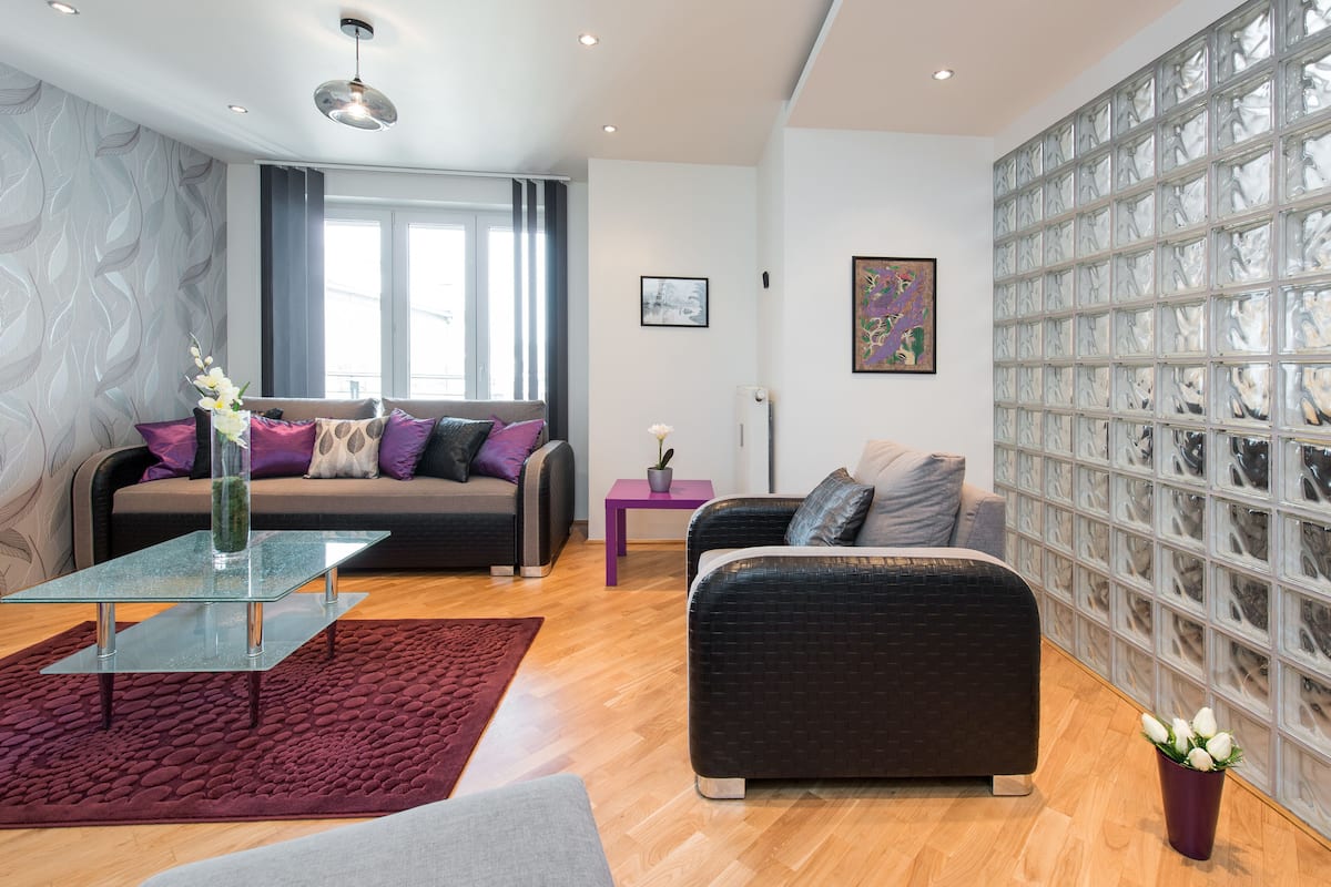 Ein modernes Wohnzimmer mit einer Couch, einem Glastisch und einer Wand mit Muster.