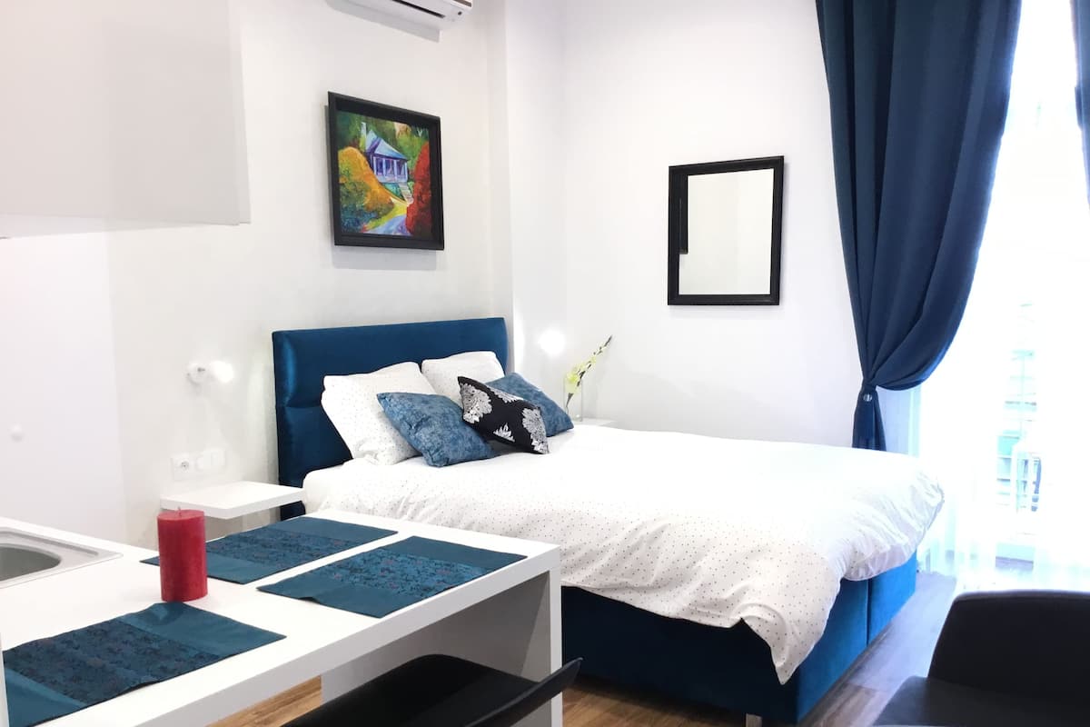 Ein modernes Hotelzimmer mit Bett, Nachttisch und Schreibtisch.