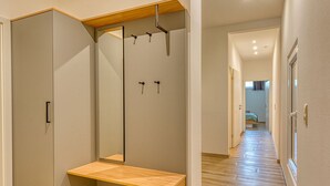 Un pasillo con un banco de madera, un espejo y un armario.