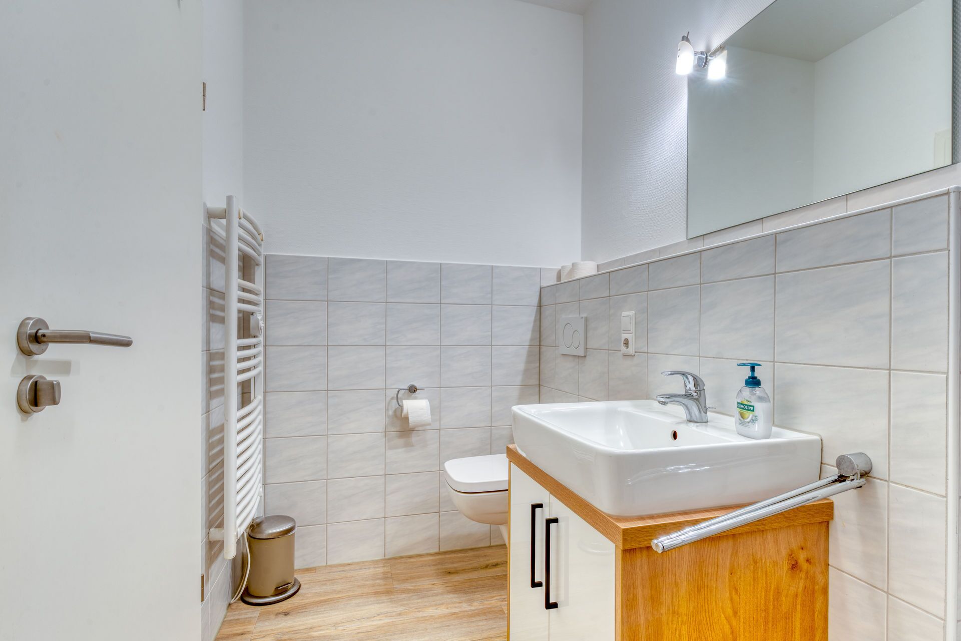 A bathroom with a white sink, a mirror, and a toilet.