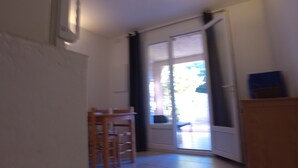 Una habitación con puerta de cristal corredera que da a un balcón, una silla de madera y una mesita.