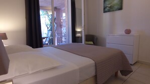 Habitación de hotel con cama, escritorio, silla, cómoda y vistas al exterior.
