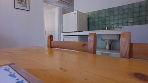 Una mesa de comedor de madera con sillas, un refrigerador blanco, un salpicadero de azulejos y una puerta que da a otra habitación.