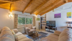 Ein gemütliches Wohnzimmer mit Holzboden, einer Sofagarnitur, einem Fernseher und einem Kamin.