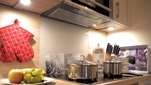 A kitchen with a stove, pots, a plate of fruit, and a red oven mitt on the counter. - Ground floor/quiet/WLAN/terrace with garden and the sound of waves/holiday from day 1 (Börgerende)