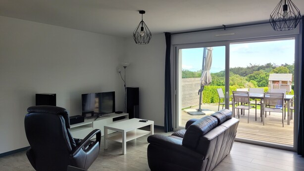 A modern living room with a flat-screen TV, a sofa, a coffee table, and a dining area with chairs and a table. - House in Crozon between the village and the beaches. (Crozon)