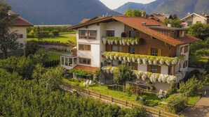 A two-story house with a balcony, surrounded by lush greenery and mountains in the background. - Vineyard apartments with magnificent view and Brixen South Tyrol Guest Pass (Raas)