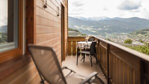A balcony with a table and chairs, overlooking a mountainous landscape. - Vineyard apartments with magnificent view and Brixen South Tyrol Guest Pass (Raas)