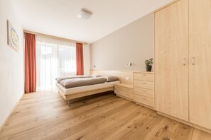 Een slaapkamer met een bed, een houten garderobe en een raam met gordijnen.