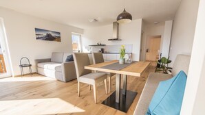 A modern living space with a dining area, sofa, and a kitchen in the background. - Vineyard apartments with magnificent view and Brixen South Tyrol Guest Pass (Raas)