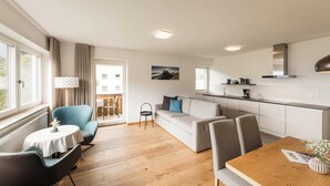 A modern apartment with a dining area, sofa, kitchen, and a balcony with a view. - Vineyard apartments with magnificent view and Brixen South Tyrol Guest Pass (Raas)