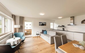 En modern lägenhet med matplats, soffa, kök och en balkong med utsikt.