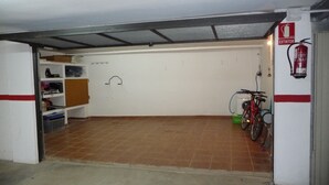 A garage with a bicycle, shelves with items, and a fire extinguisher. - Apartment 150 m beach with garden and garage (llança)