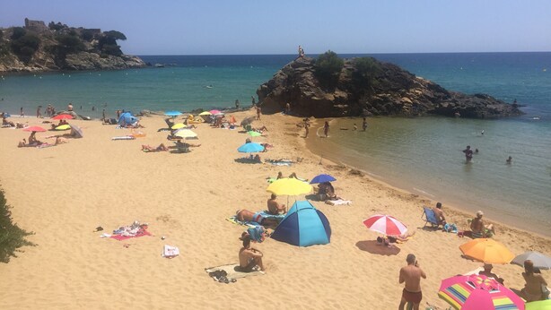 A beach with people sunbathing, umbrellas, and a rocky outcrop in the background. - Apartment 150 m beach with garden and garage (llança)