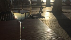 A glass of white wine on a table with a view of the sunset and palm trees. - Apartment 150 m beach with garden and garage (llança)