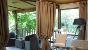 Ein Zimmer mit einer Holzterrasse, Korbmöbeln, einem weißen Schaukelstuhl und einer Lampe.