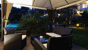 An outdoor patio area with wicker furniture, a glass table, and a pool in the background. -  high standing *** villa with heated pool, near downtown (Porto-Vecchio)