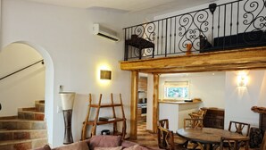 A spacious living area with a wooden staircase, a dining table with chairs, and a sofa with cushions. -  high standing *** villa with heated pool, near downtown (Porto-Vecchio)