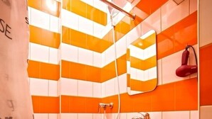 Un baño con azulejos naranja y blanco, un lavamanos blanco y un inodoro.