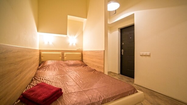 Un dormitorio con cama, una toalla roja, una lámpara de pared y una puerta.