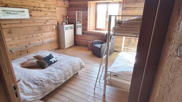 Een houten kamer met een stapelbed, een bureau, een stoel en een raam.