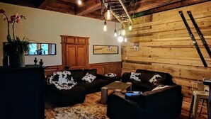 Una sala de estar acogedora con paredes de madera, un conjunto de sofás y una mesa de centro.