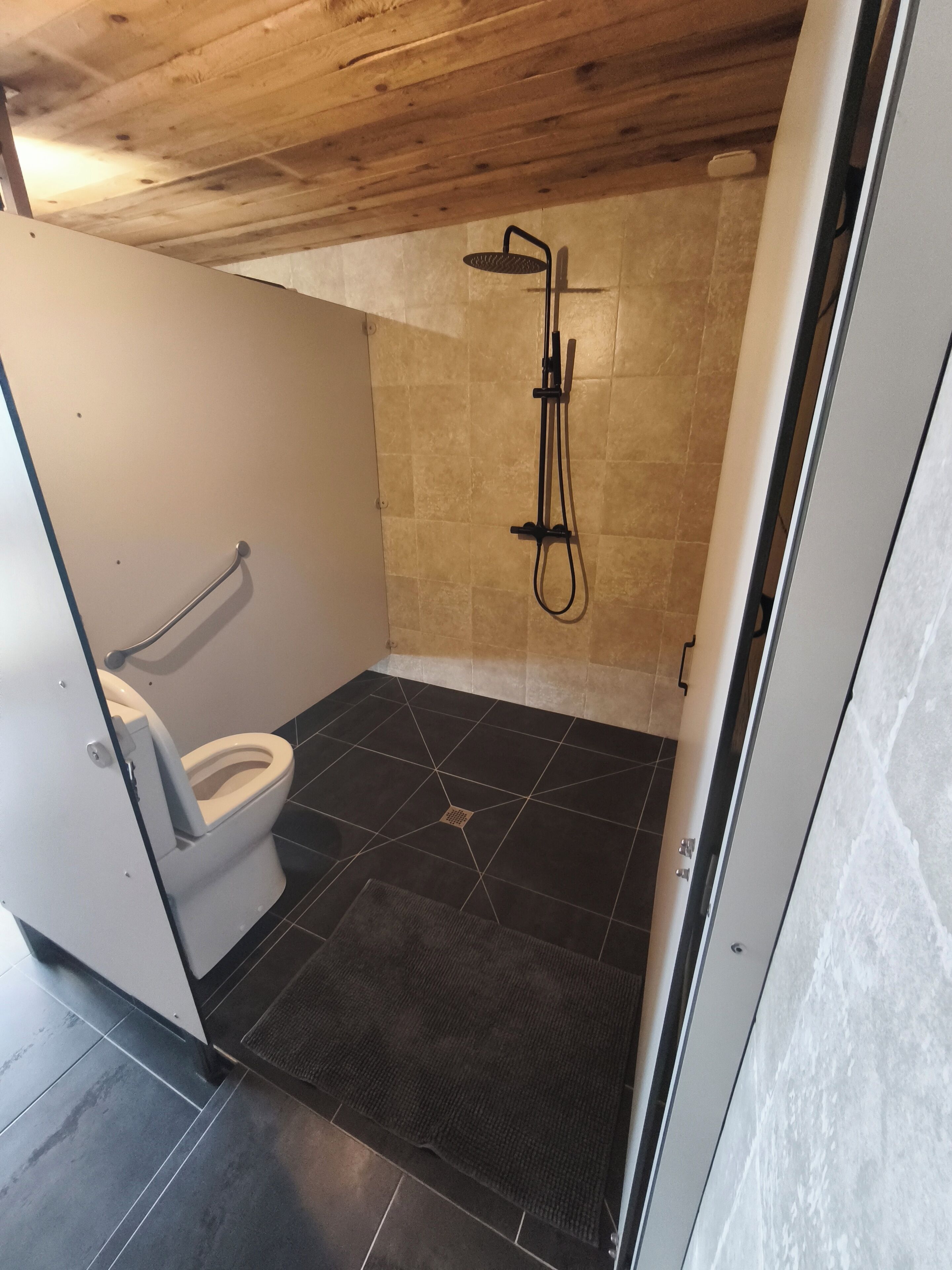 A small, compact bathroom with a shower, a toilet, and a sink.