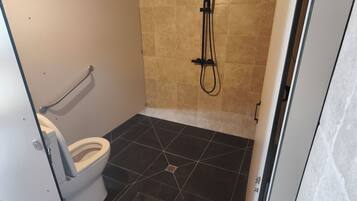 A small, compact bathroom with a shower, a toilet, and a sink.