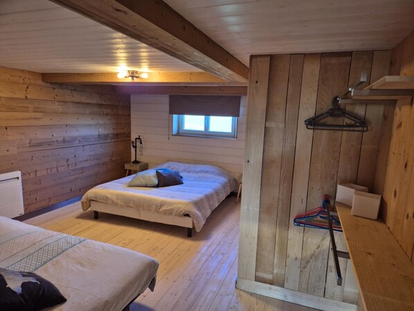 Une chambre confortable, aménagée dans le style d’un chalet, avec un lit, une petite table et une fenêtre.