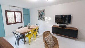 A dining area with a wooden table and chairs, a television, and a cabinet. - Banan'appart - the magnificent Hermitage T3 with fully renovated garden (L'Ermitage-Les-Bains)
