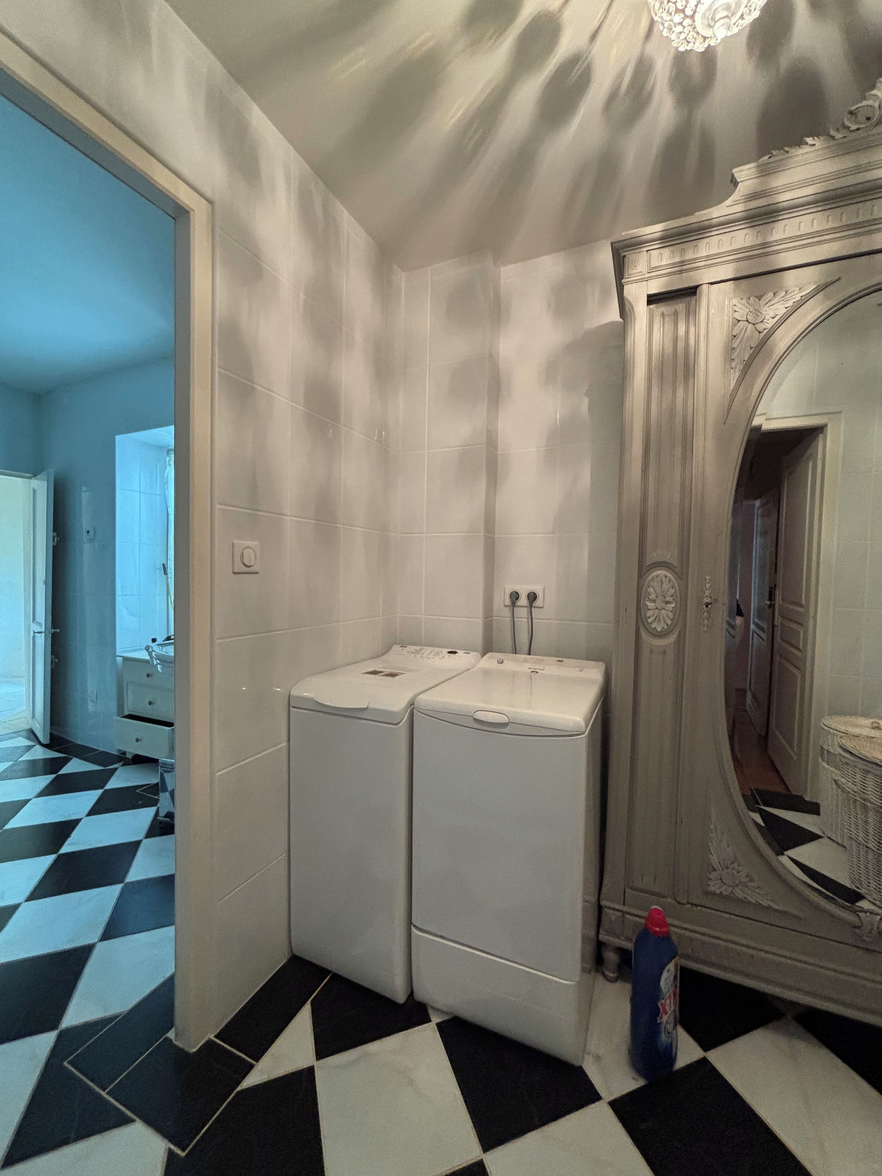 Un baño con dos lavamanos, un espejo y una lavadora.
