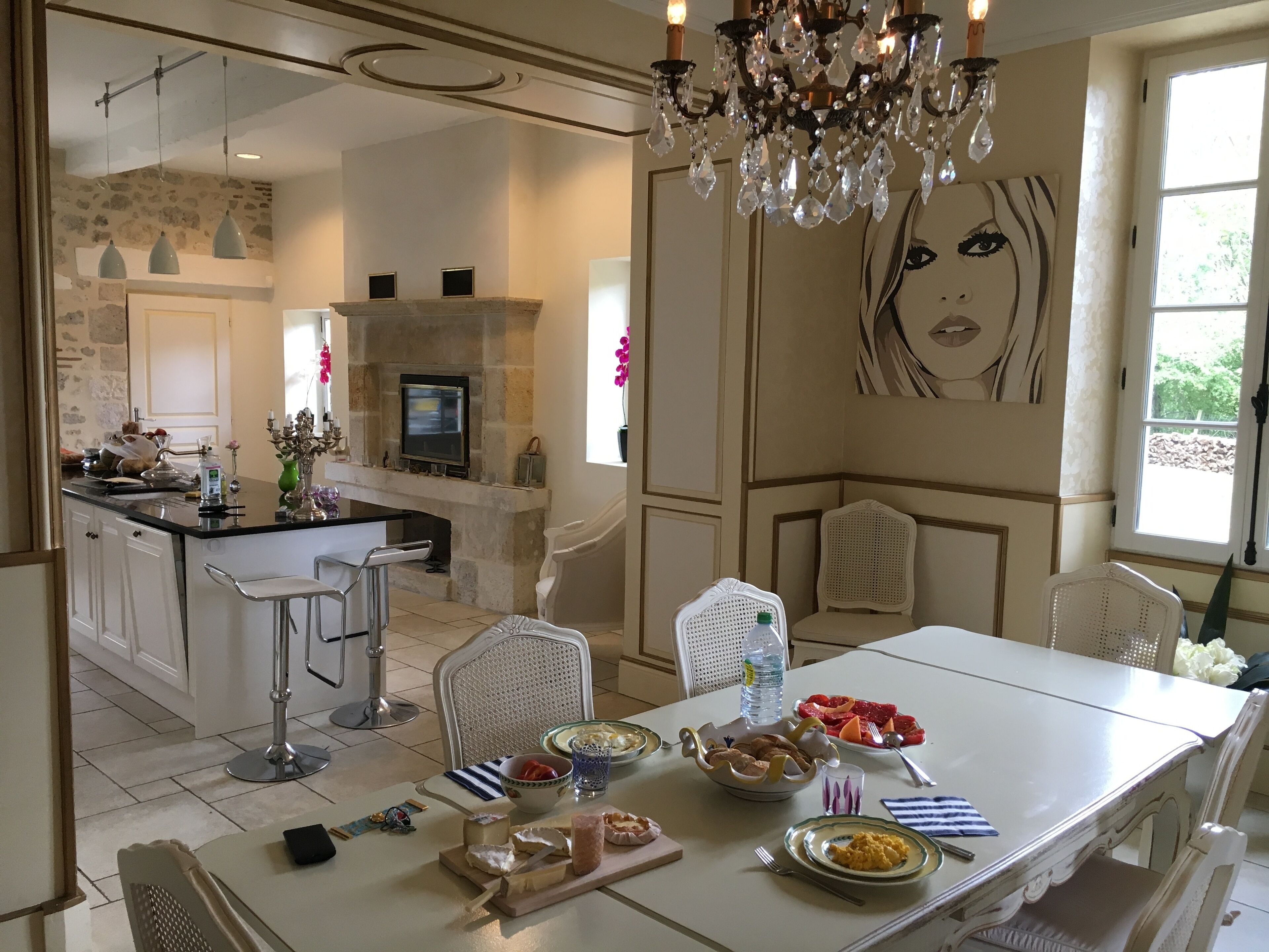 Una cocina moderna con protector de piedra, una isla central y una zona de comedor con mobiliario blanco.