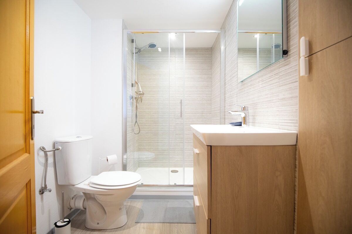A modern bathroom with a toilet, shower, and sink.
