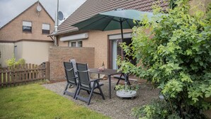 A patio with a table and chairs, a potted plant, and a brick house with a tiled roof. - Just let your mind wander: the quiet location of this holiday Doppelha (Carolinensiel)