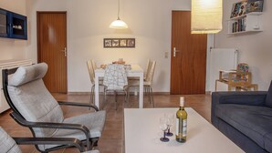 A living room with a dining area, a sofa, and a table with a bottle and glasses. - Just let your mind wander: the quiet location of this holiday Doppelha (Carolinensiel)