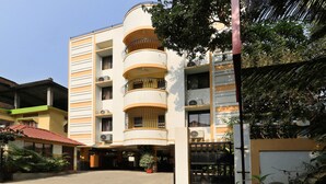 A multi-story building with balconies, a covered entrance, and a gated driveway. - Treebo Umal Homestay Ganeshguri (Guwahati)