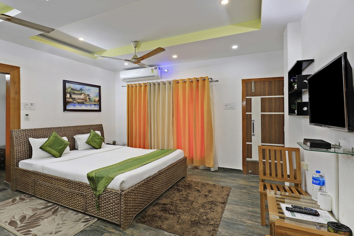 A hotel room with a bed, a television, a desk, and a bathroom.